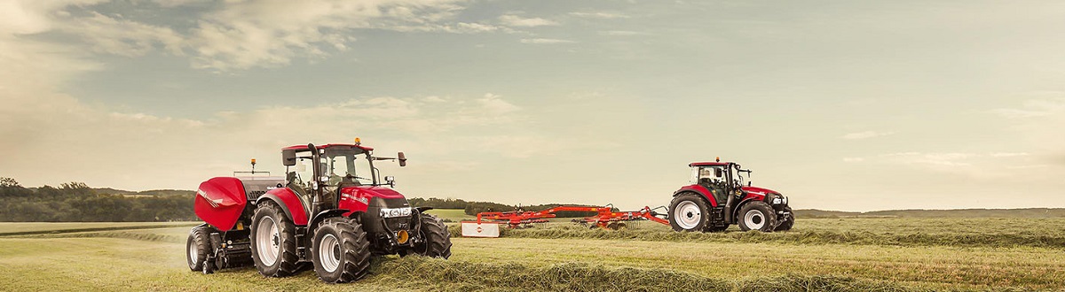 Two red tractors baling hay in a field 